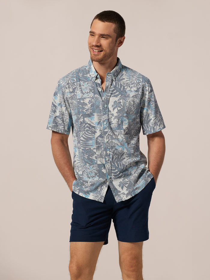 Blue floral short-sleeve shirt and navy shorts, front view, hands in pockets .