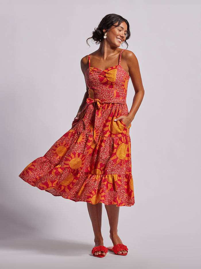 Yellow floral-print sleeveless Amalfi dress with matching sandals, front view, hand in pocket.