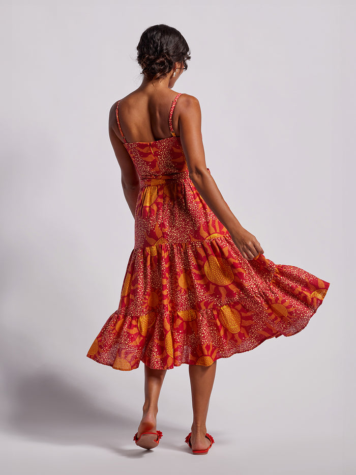 Bold red and orange floral-print maxi dress with twirling skirt, barefoot view .