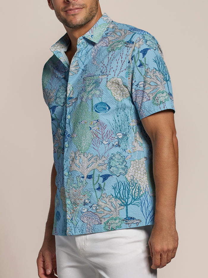 Aquatica coral & fish-print UPF long-sleeve shirt with white pants, front view.