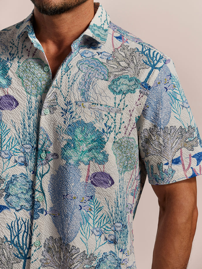 Light blue coral reef & fish-print cooling shirt, front view, worn by man in both images.