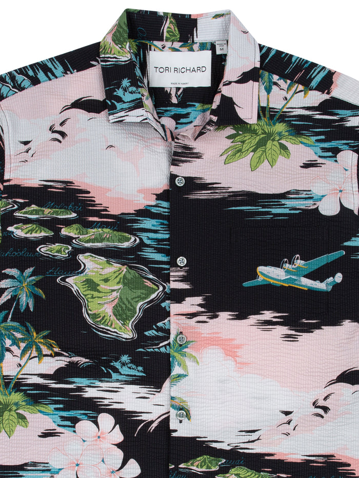 Pink and black island-print cotton shirt, close-up shows flowers and seaplane detail.