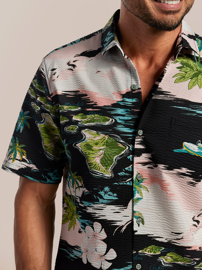 Pink, black, green & blue tropical short-sleeve shirt with island and plane print island and wave-print short-sleeve shirt, chest-up view.
