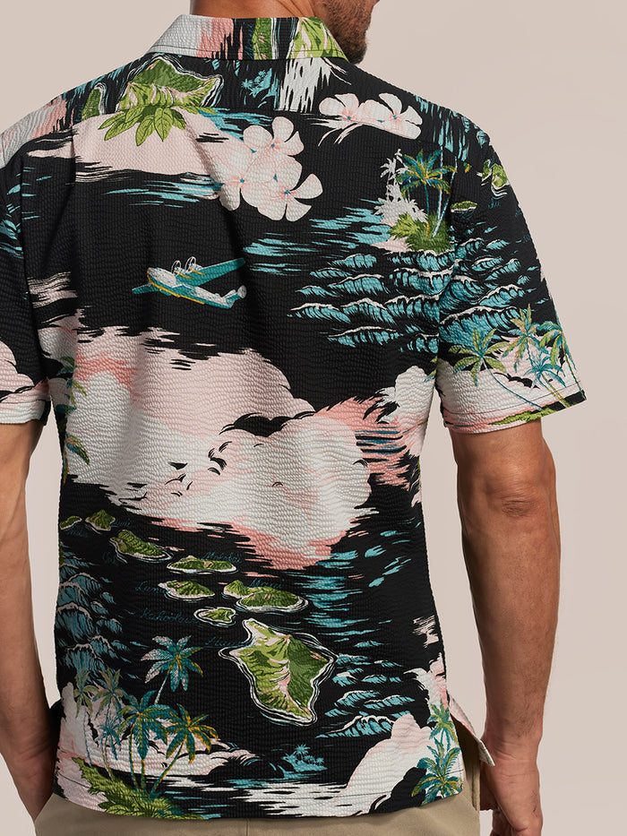 Pink, black, green & blue tropical short-sleeve shirt with island and plane print shirt, back view.