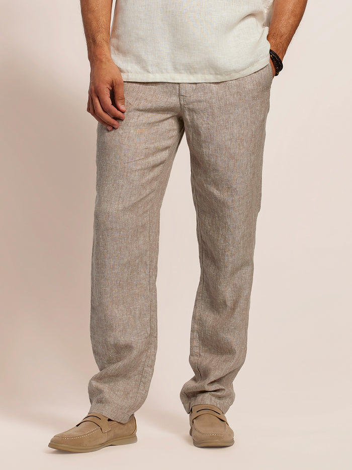 Taupe linen pant and white shirt on model, brown loafers, hand in pocket, front view