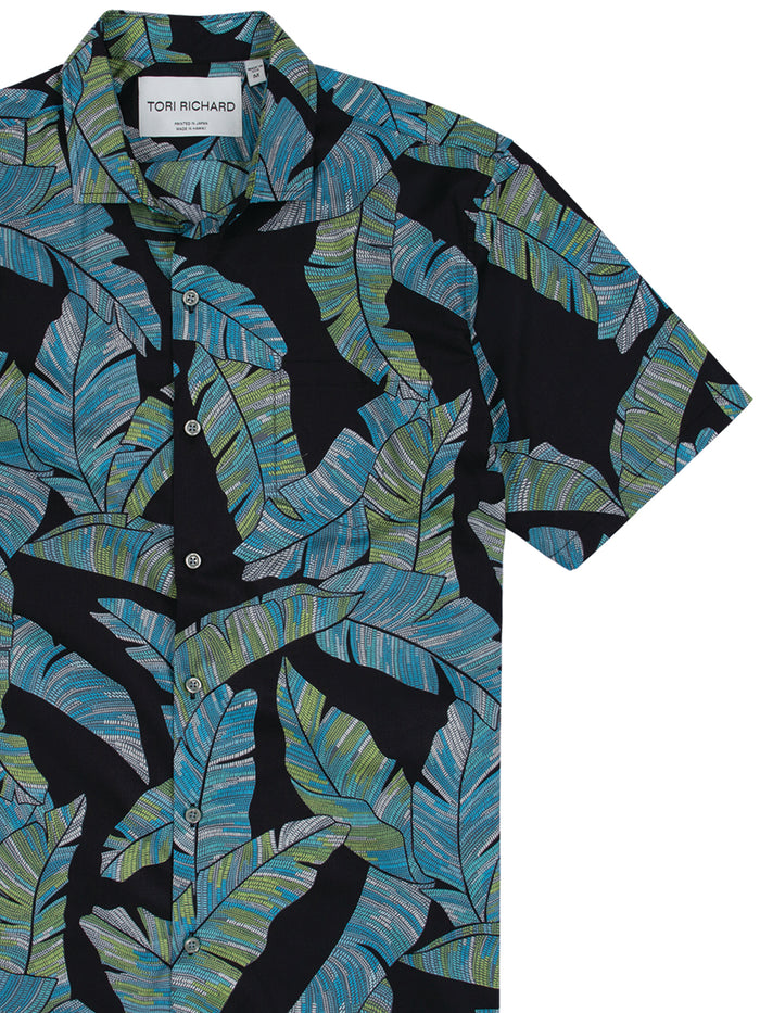 Black shirt with blue-green tropical leaf print, short sleeves, front view.