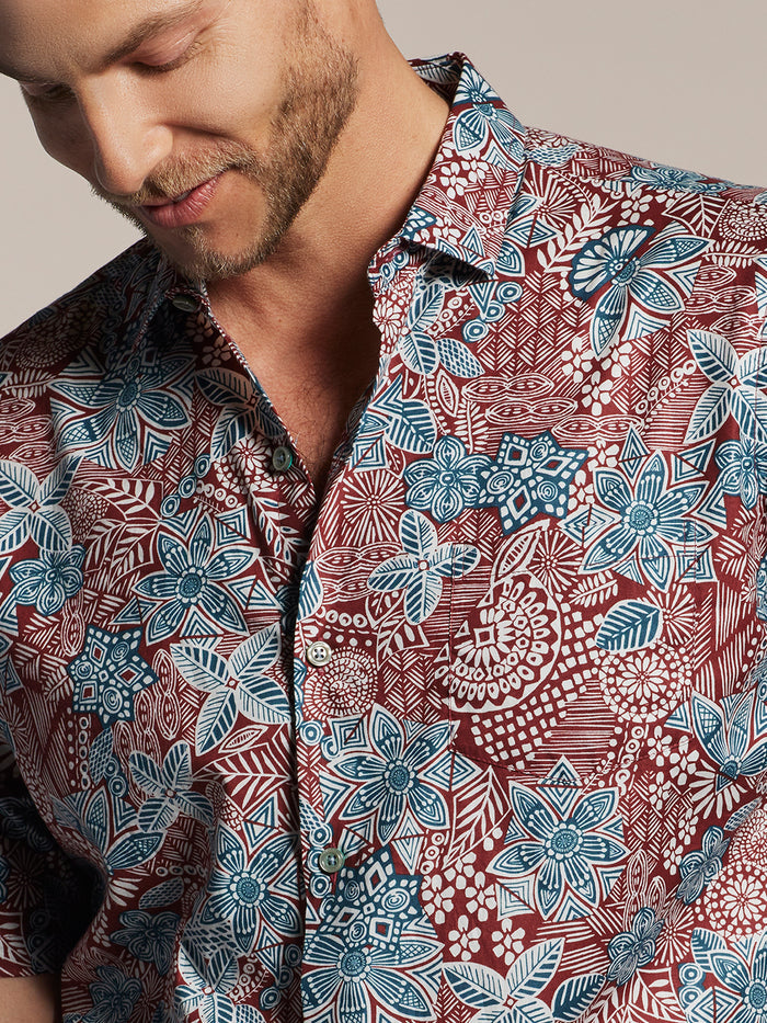 Maroon cotton shirt with blue and white doodle print, front view, man looking down.