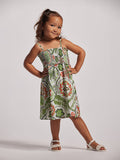 A young girl wearing a sleeveless floral dress with a smocked bodice and flared skirt, standing against a white background.