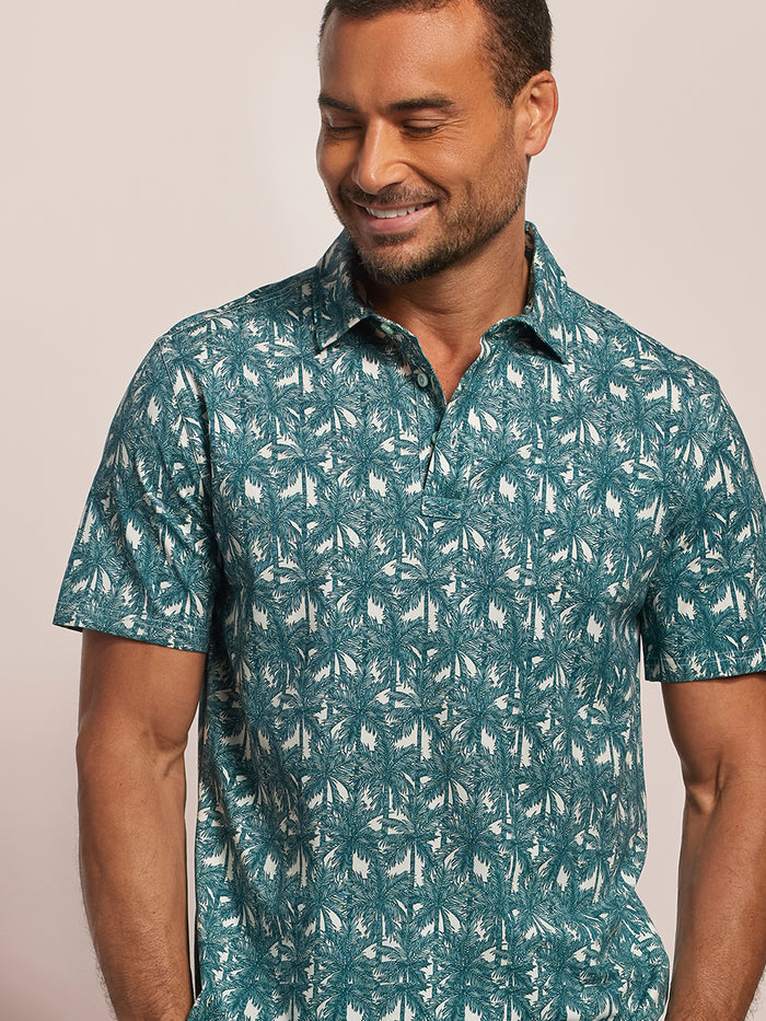 Teal tropical-print polo shirt, man looking down and to the left.