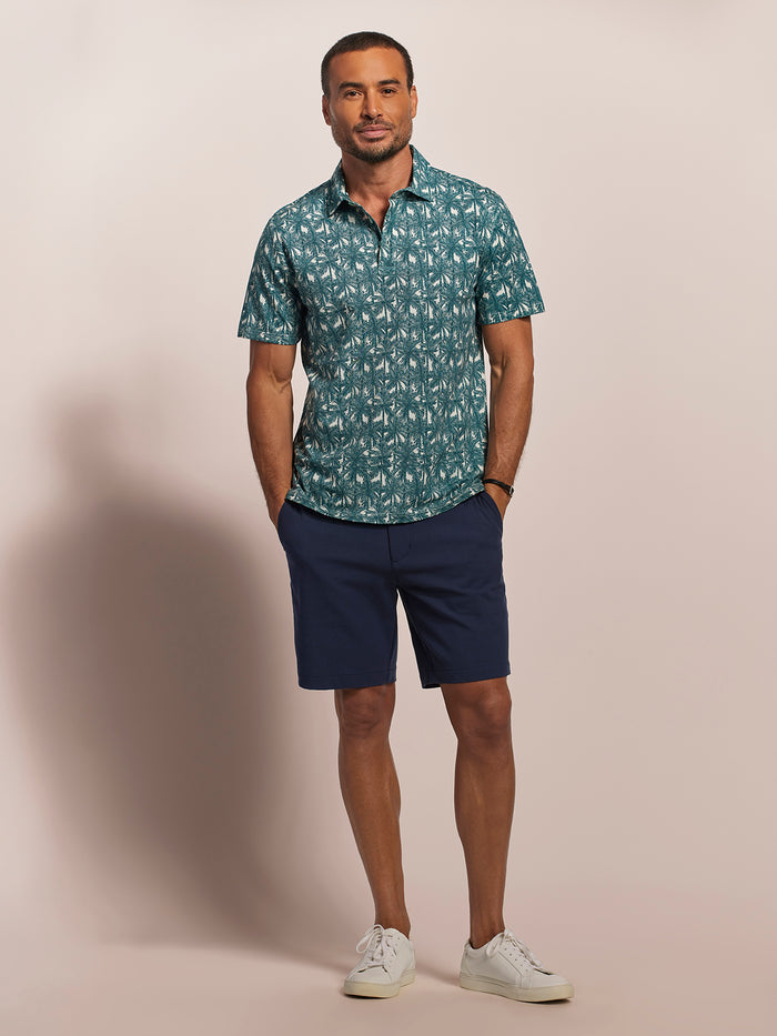 Navy palm-print short-sleeve polo shirt with navy shorts and white sneakers, full front view.