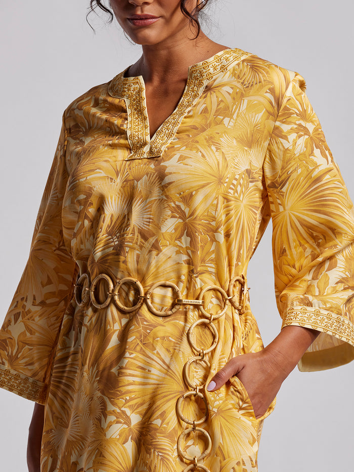 Yellow solid caftan dress with bamboo belt, side view, hand in pocket.