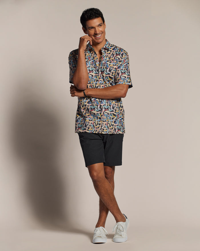 Blue surfboard-print short-sleeve shirt, black shorts, white sneakers, front view.
