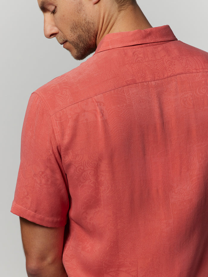 Red coral jacquard short-sleeve shirt, rear view; model looks over left shoulder.