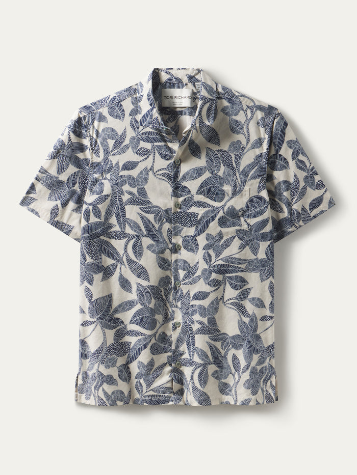 White short-sleeve button-up shirt with blue plumeria print, flat lay front view.