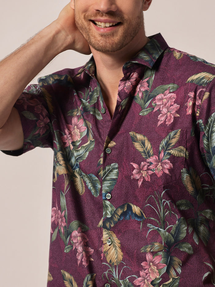 Maroon short-sleeve shirt with purple orchid and green leaf print, front view.