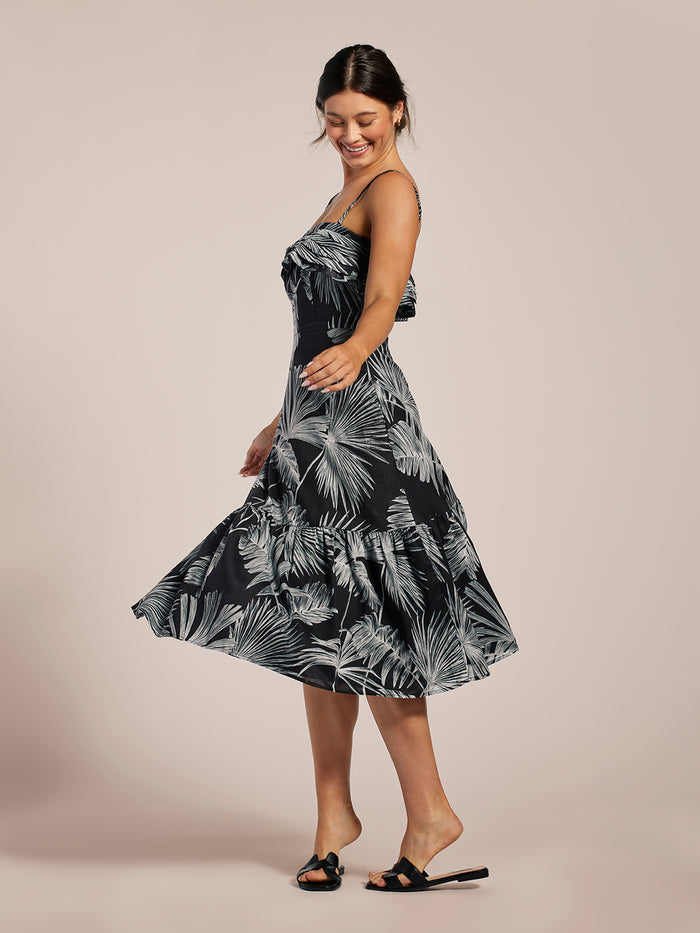 Black dress and white palm-print sleeveless midi-length dress, twirling front view.