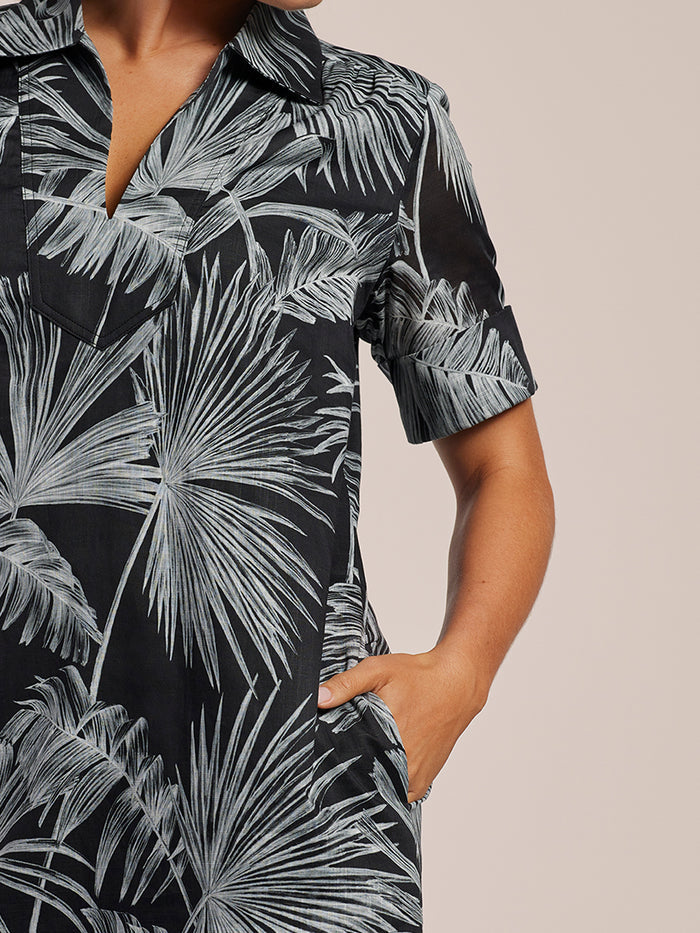 Black and white tropical leaf-print short-sleeve dress with hand in pocket.