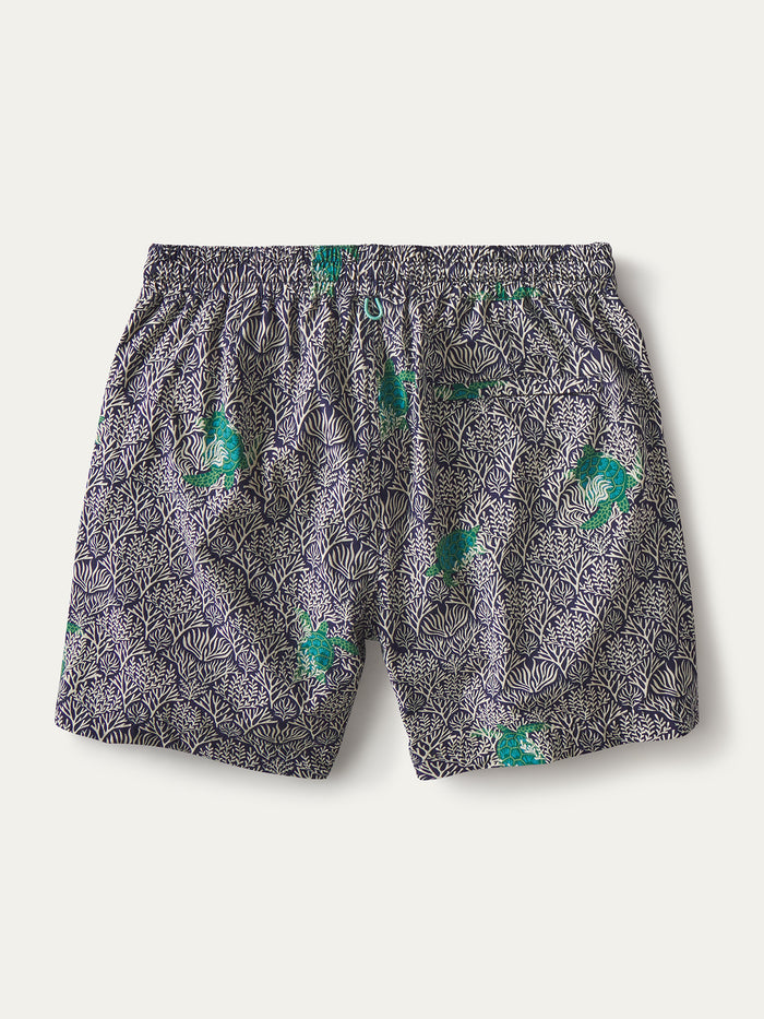 Navy and white coral-print swim short with green fish accents, corals and sea turtles' pattern, shown flat in both images.