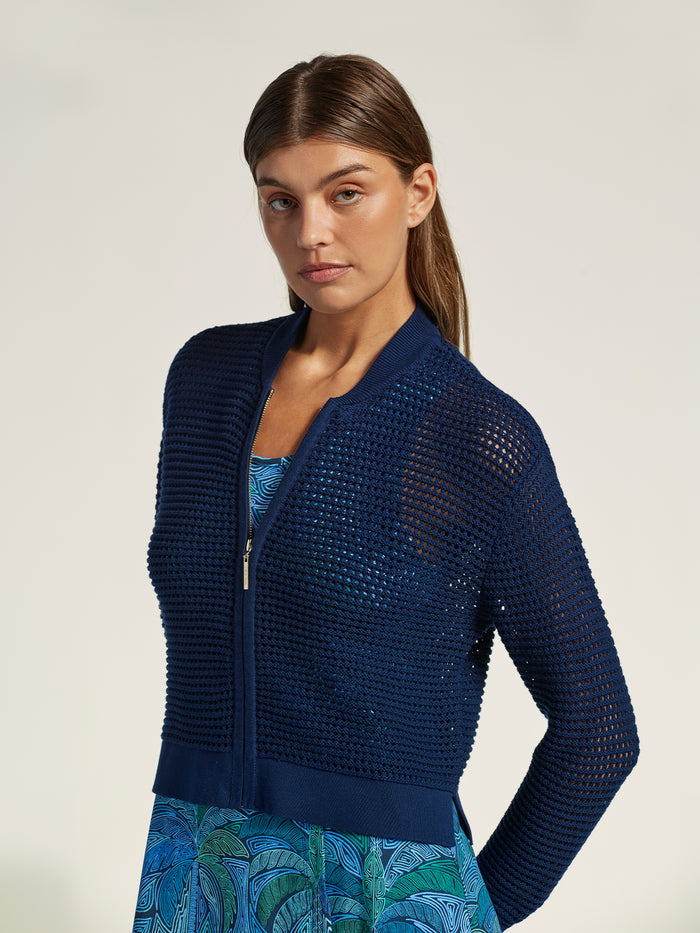 Blue solid knit cardigan over blue patterned dress, full front view.