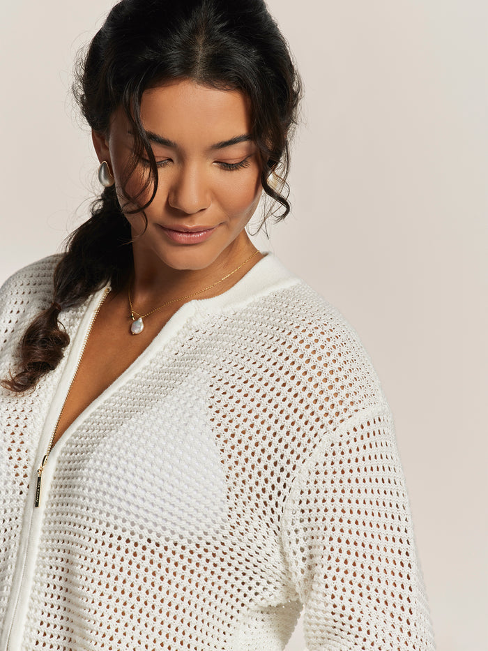 Cream knit Umi cardigan, worn by woman with pearl jewelry and wavy hair, front view.