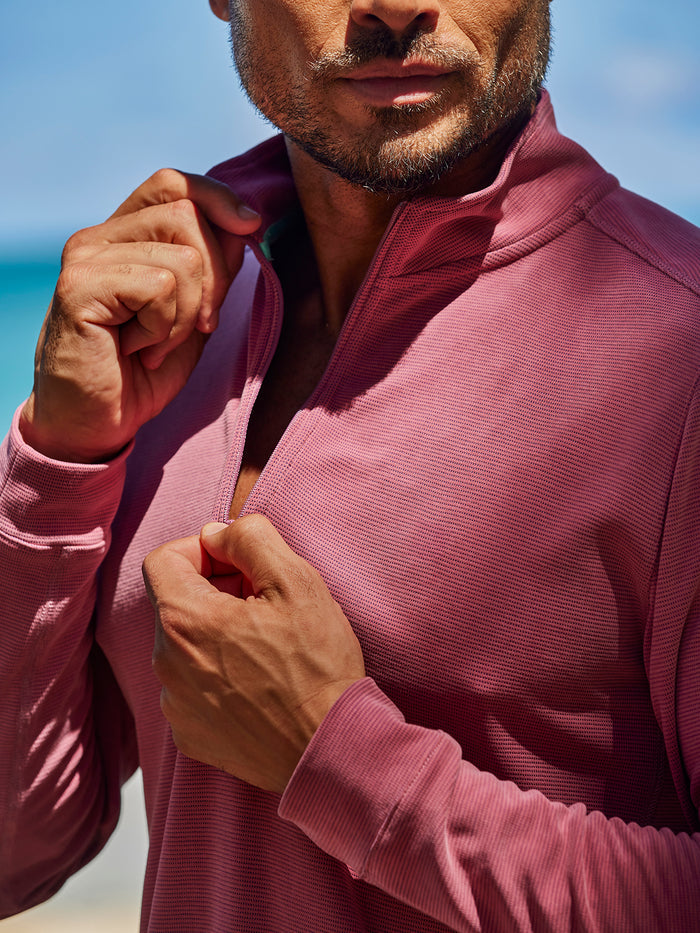 Light pink solid quarter-zip pullover, man unzipping collar, outdoor front view.