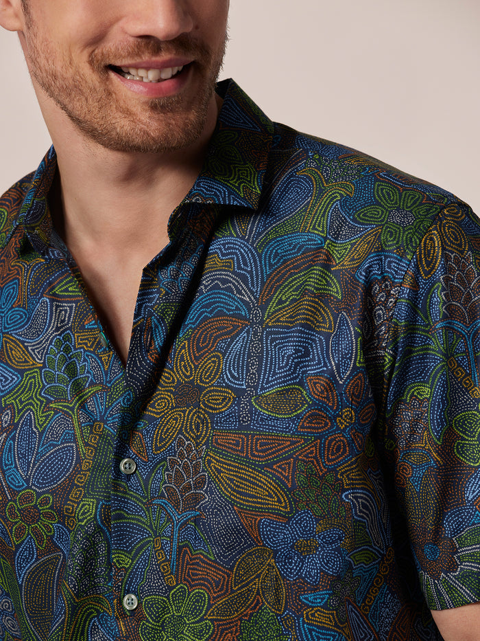 Multicolor abstract floral and geometric short-sleeve shirt, front view on smiling man.