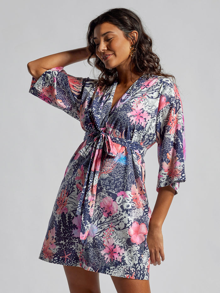 Coral floral-print Allegra dress, sleeveless, model poses with one arm raised, front view.