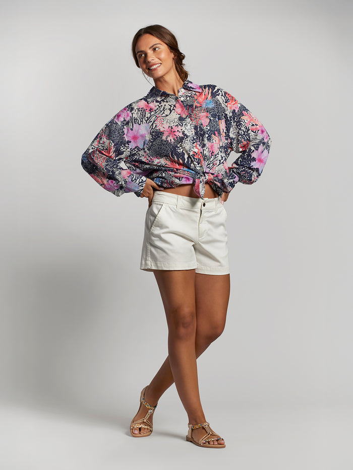 Coral floral-print relaxed-fit blouse, front view, with white shorts and sandals.