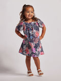 A young girl wearing a short-sleeved floral dress with a mix of pink, blue, and other colors.