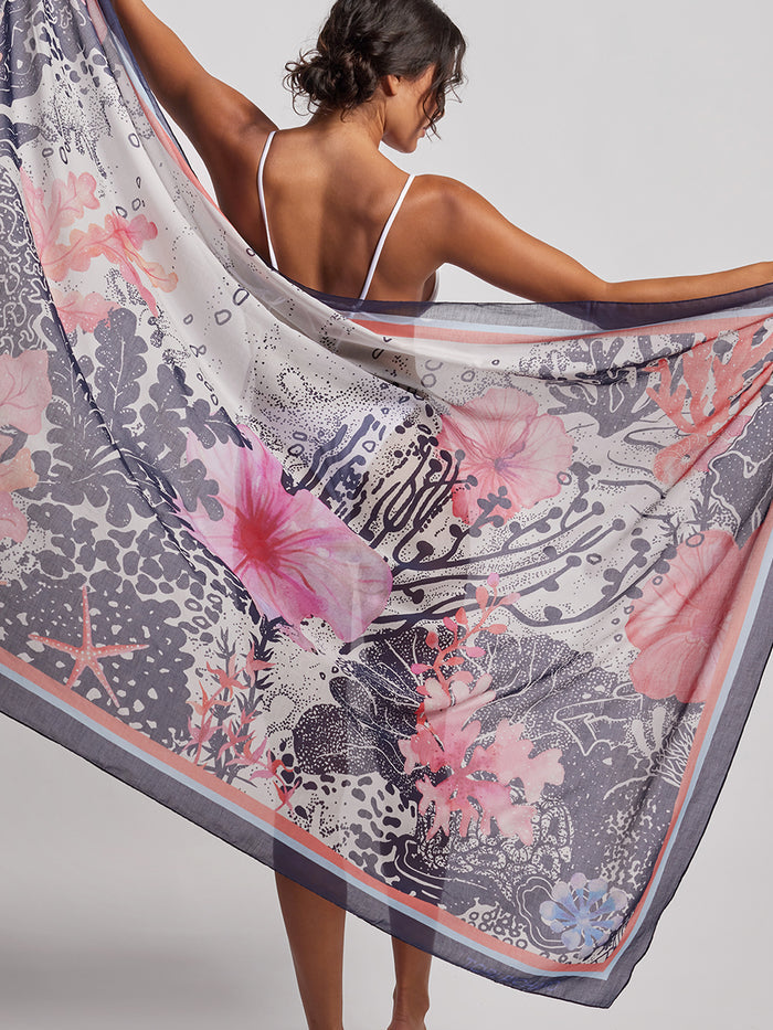 Coral, pink, and purple floral-print pareo, back view with woman holding fabric out.