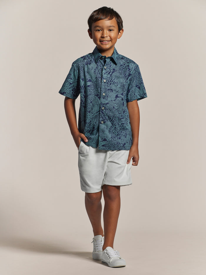 Light short-sleeve shirt, white shorts, sneakers, front view, hand in pocket (shown in two images).