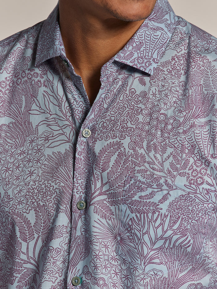 Light blue cotton lawn shirt with purple botanical print, chest and shoulders view.