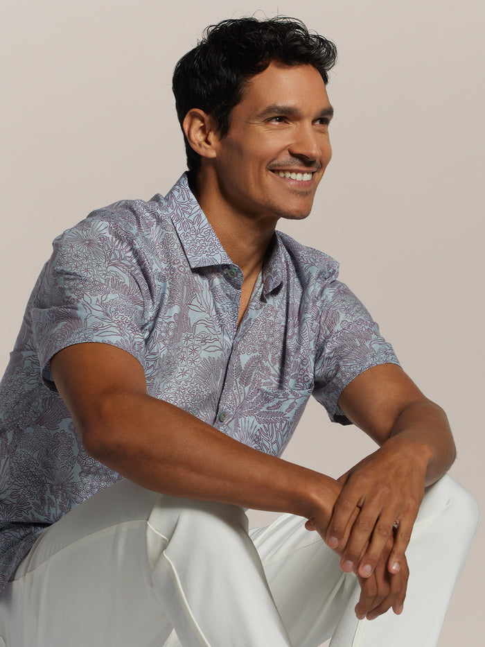 Coral graphic-print short-sleeve shirt and white pants, seated, front view (Image 1 & 2).