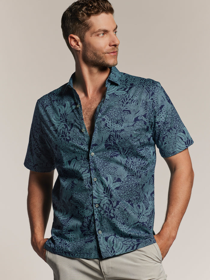 Blue Coralcopia-print short-sleeve shirt, front view, man with hands in pockets (shown twice).