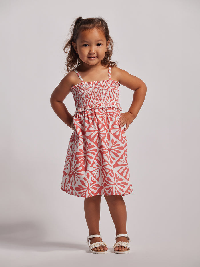 Coral smocked-bodice Adalei dress, front view; girl poses hands on hips.