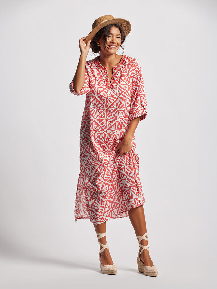 White nad pink patterned caftan dress, front view, with straw hat and espadrilles.
