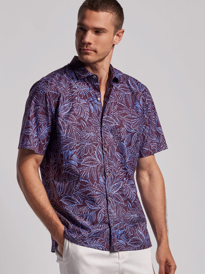 Purple batik-style button-up with blue leaf print, side view on a model.