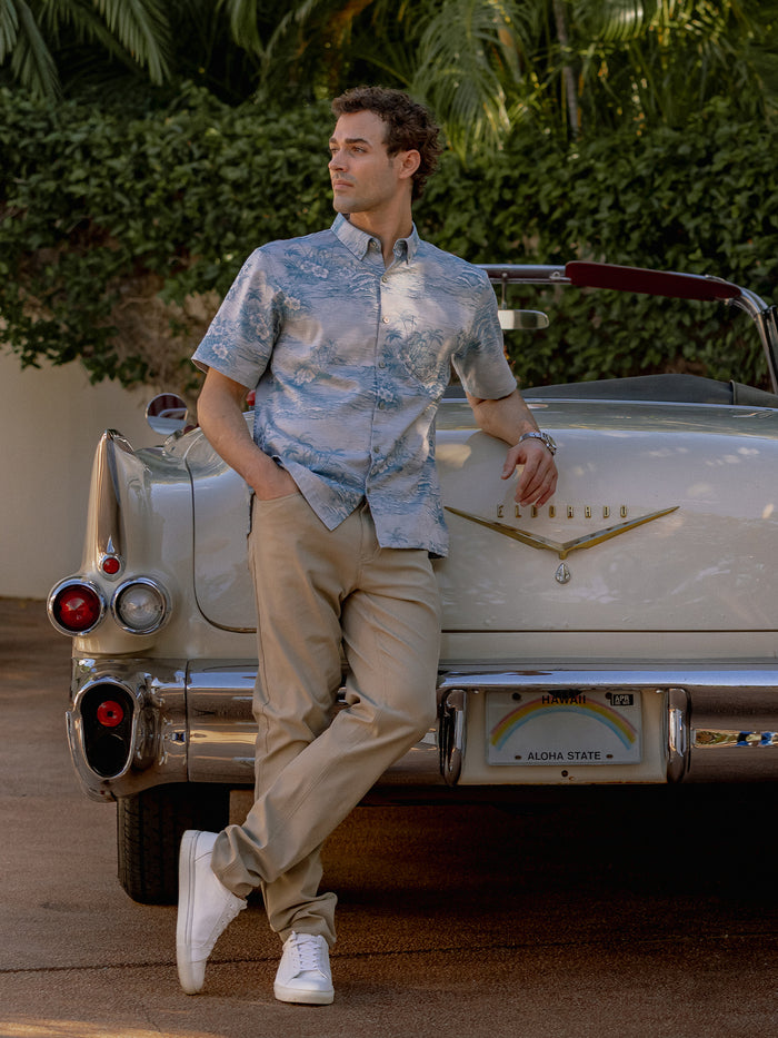 White scenic jacquard short-sleeve shirt, man leaning on vintage Cadillac, outdoor view.