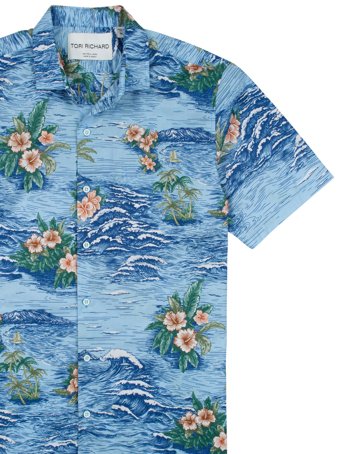 Blue Hawaiian shirt with pink floral, palm tree, and sailboat print, front view.
