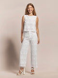 White sleeveless crop top and white palm eyelet pants, front view.