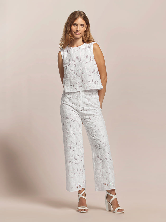 White eyelet-pattern top and pants set with heeled sandals, shown from the front.