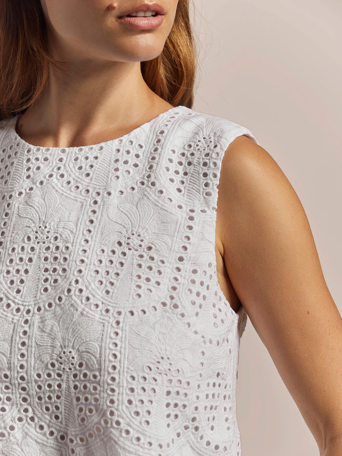 White geometric-embroidered sleeveless shell top, close-up frontal view.