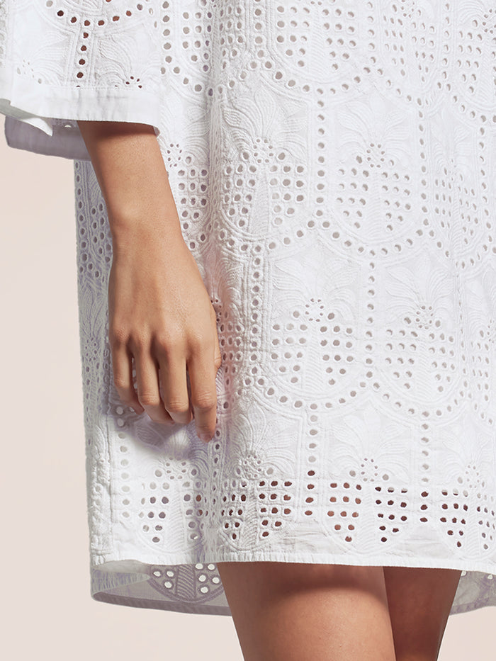 White lace dress with a sheer overlay on a light background