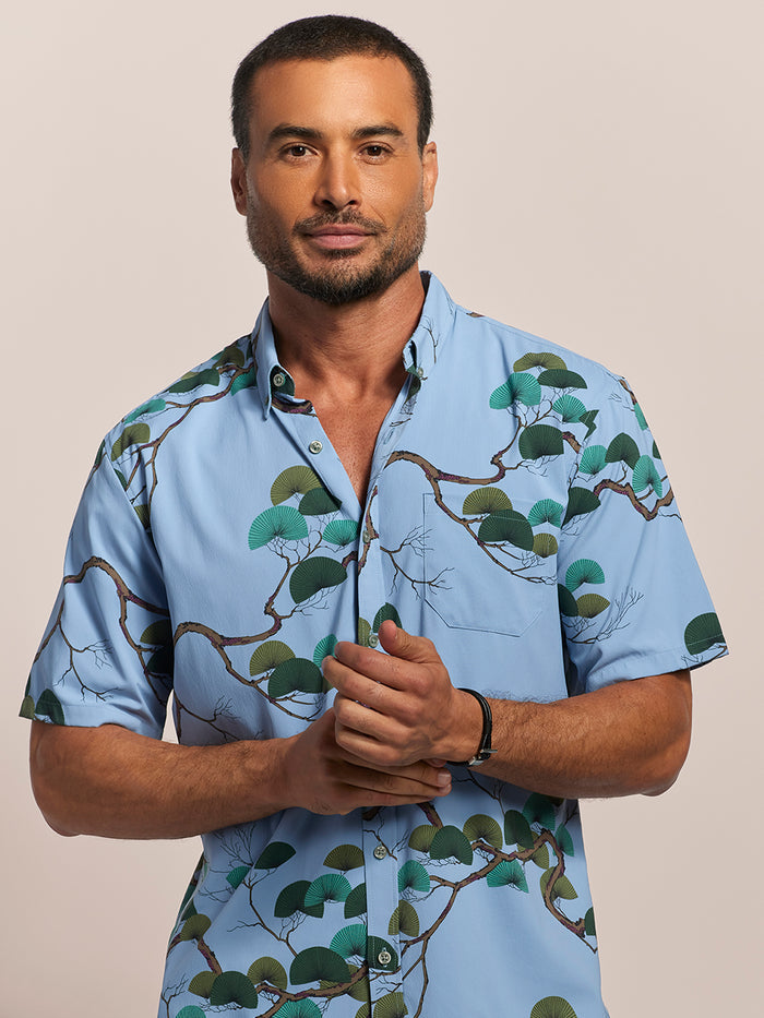 Blue short-sleeve shirt with Japanese pine tree print, closed-up front view.
