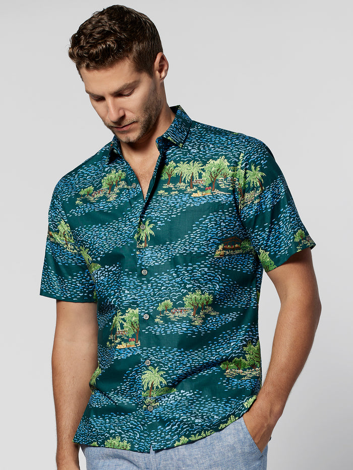 Green and blue vegetable-print lightweight cotton short-sleeve shirt, model looking down, front view.