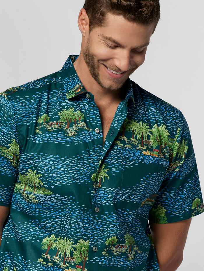 Blue tropical island and ocean print short-sleeve shirt, front view on smiling man.