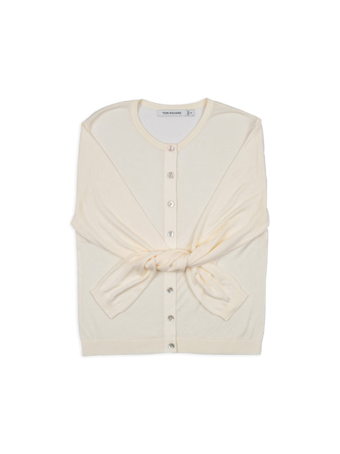 Cream knit cardigan, folded with sleeves tied in front; buttons visible.