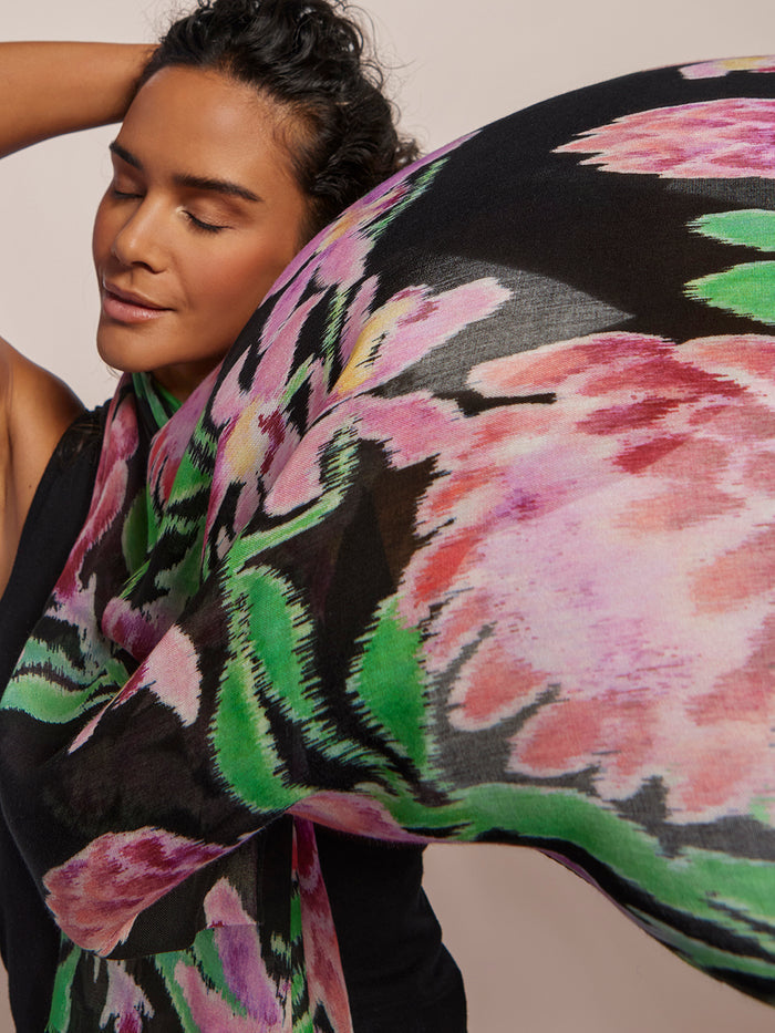 Pink, green, and black orchid-print viscose scarf, draped on woman with closed eyes.