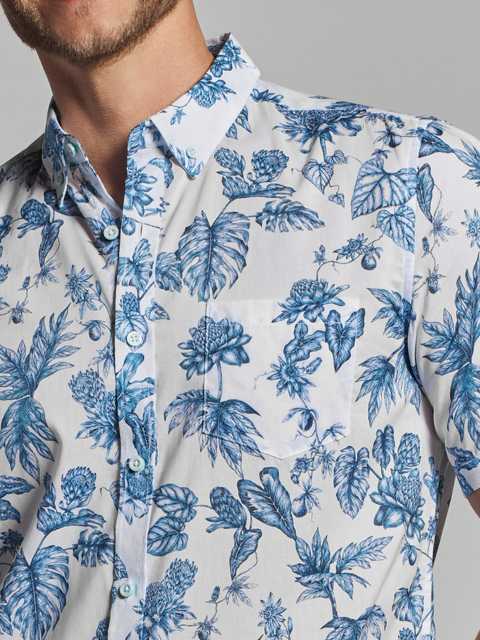 White cotton poplin shirt with blue tropical leaf and flower print, shoulders to chest view (2 images).