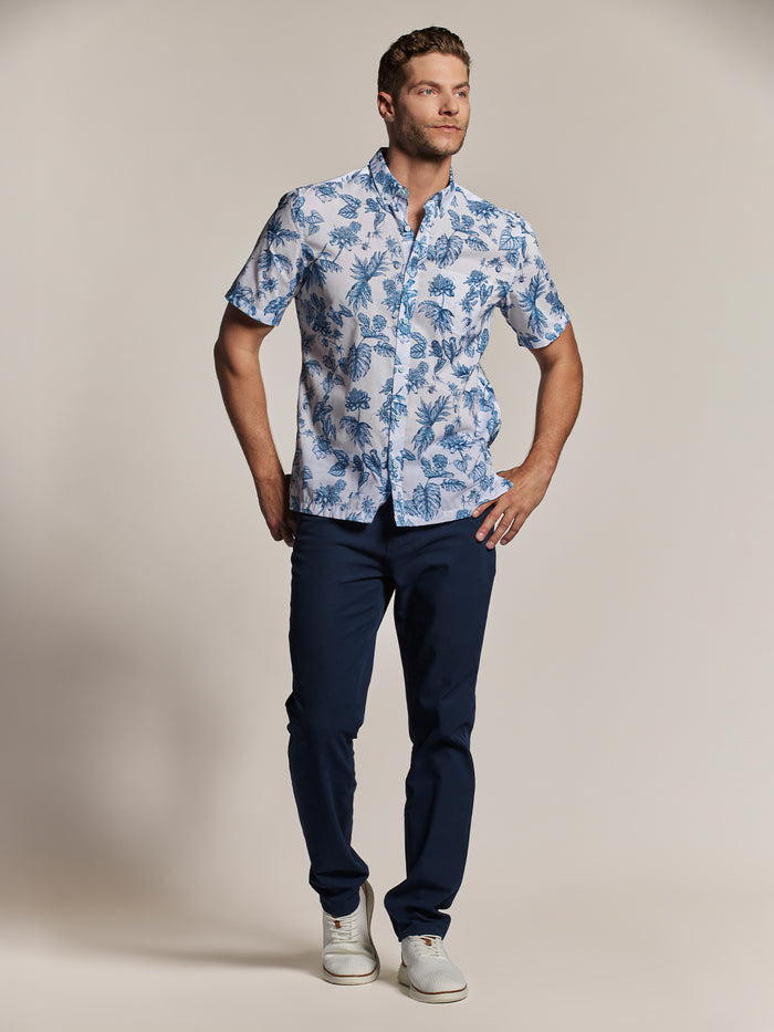 Blue floral-print short-sleeve shirt, front view with navy pants and white sneakers.